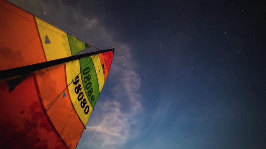 Timelapse of the night sky over the sails of a boat