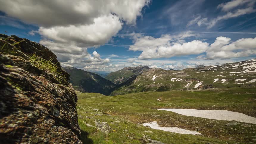 Clouds move over a lush green mountain valley