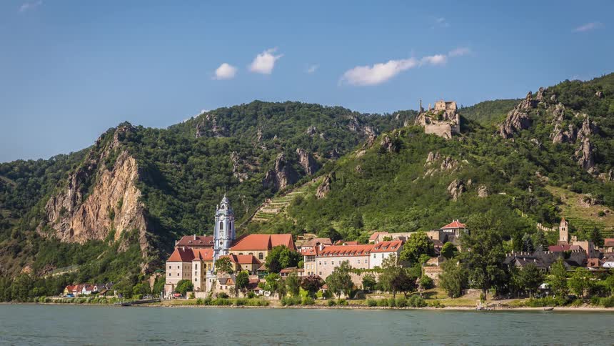 A boat sails across the water in front of a small mountain side town