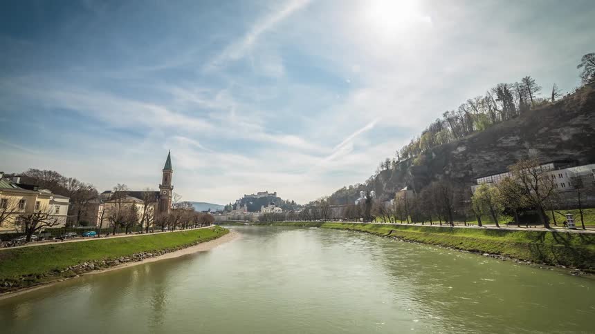 A muddy river running through a picturesque town with people walking on the paths