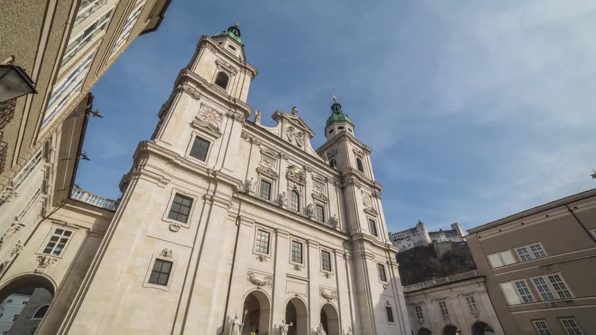 Pedestrians walk along courtyard of ornate building
