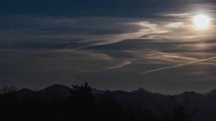 The sun rising into the sky over mountains
