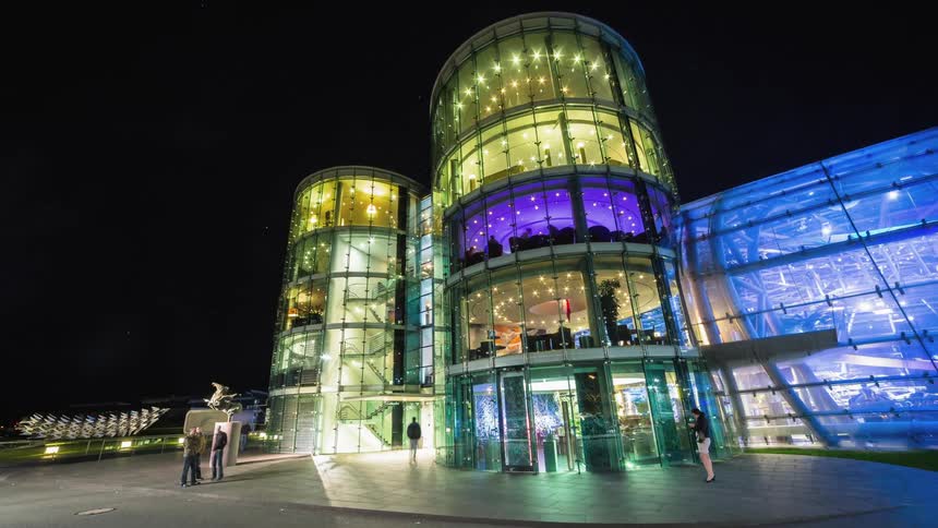 Tubular shaped glass filled building brightly lit at night
