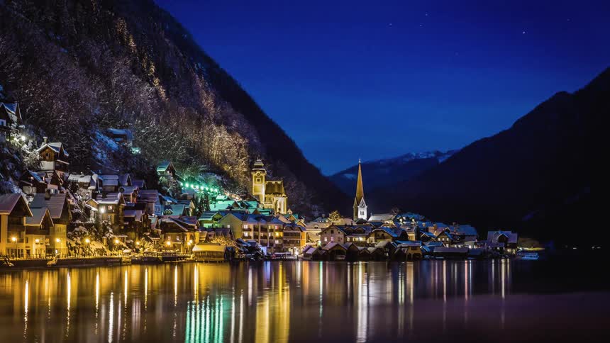 Night falls over a city that lies at the base of a mountain