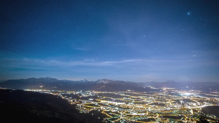 Brightly lit city in valley between mountains