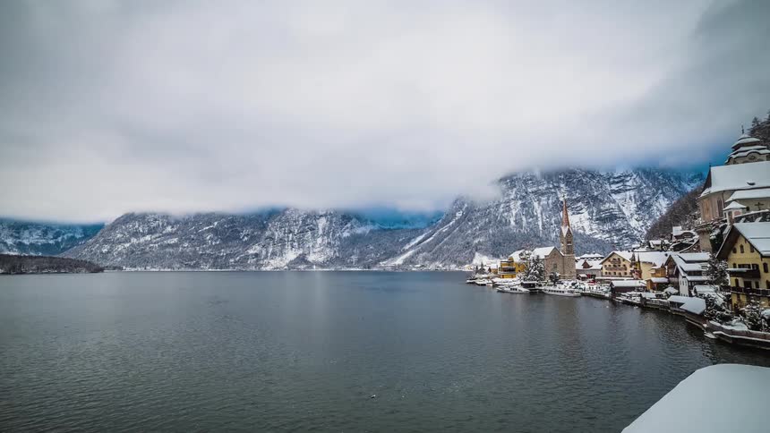 A coastal town with quaint buildings surrounded by mountains and lake