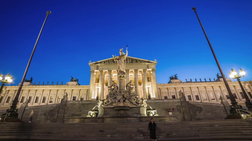 Traffic moving down a street and past a monument and government building