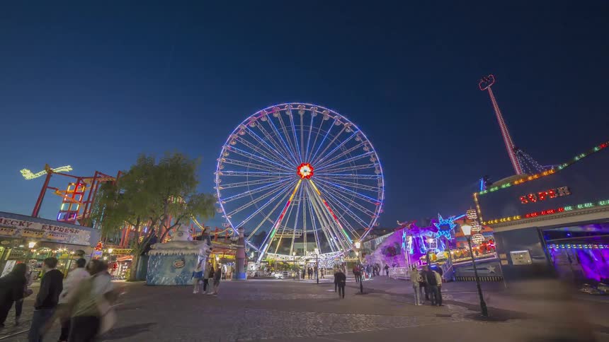 An amusement park with a large ferris wheel games rides and food attractions at night
