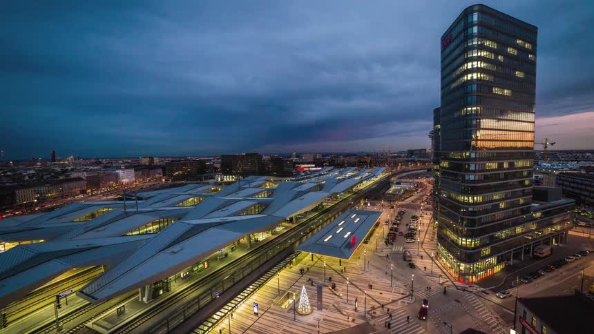 Traffic and pedestrians move along a citys streets and near a train station