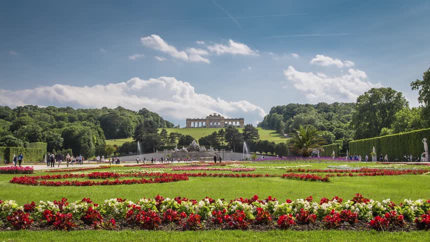Timelapse of tourists visiting a landmark garden and structure on a sunny day
