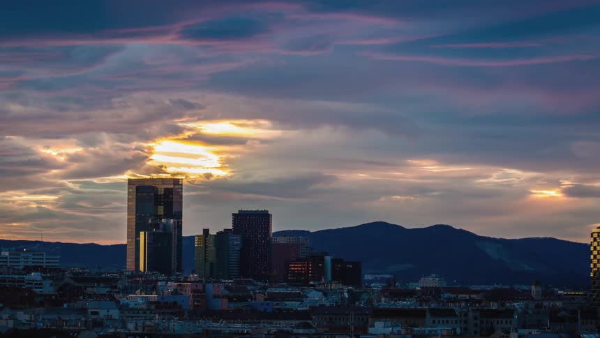 Clouds float above city skyscrapers at sunset