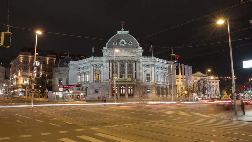 Cars and pedestrians travel on a busy city street at night