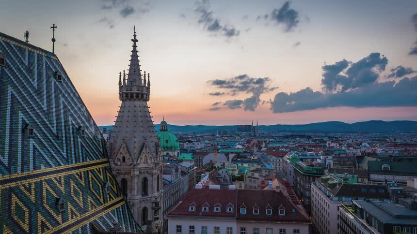 Clouds float above a cathedral and city buildings at sunset
