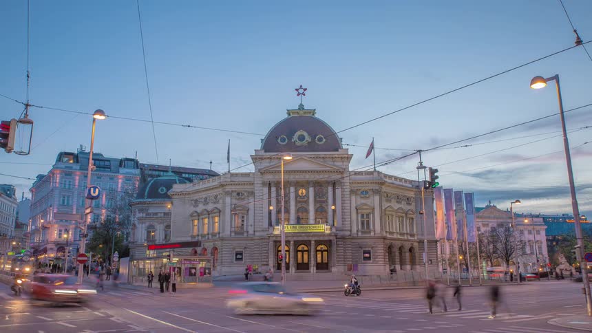 Pedestrians cars and wired trolley travel through a busy city intersection