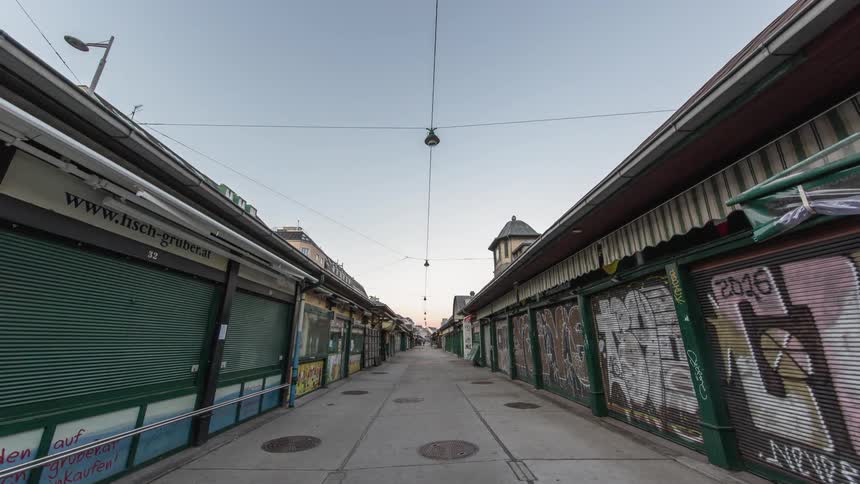Graffiti covers the front gates of businesses along a walkway