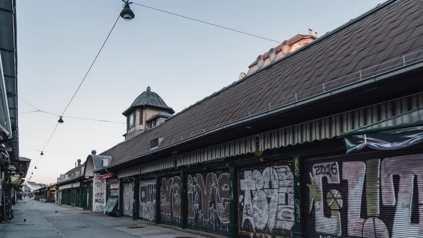 Street with graffiti on buildings with lights overhead and people passing buy