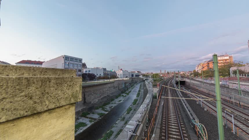 Cars and trains pass through a city as it transitions from morning to night