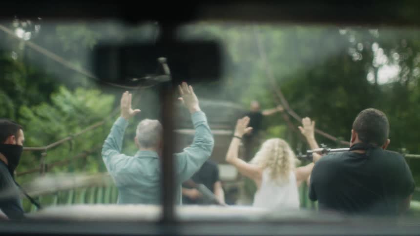 Armed men take two white people hostage on a bridge in the jungle