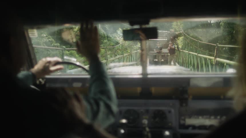 A man driving a car on a rainy road and being stopped by people with guns