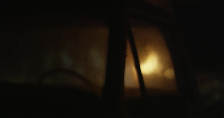 An outdoor fire is partially obstructed by a parked vehicle