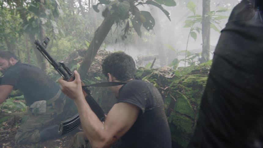 A group of men armed with assault rifles taking cover being a large downed tree trunk