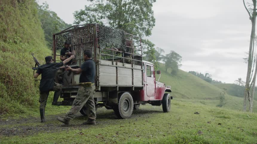 Men in camouflage pants check their guns before climbing into the back of a truck