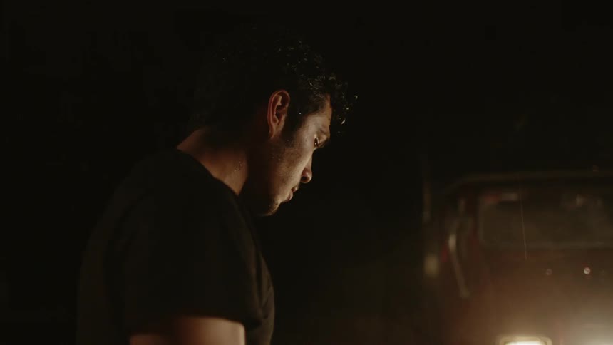 A man stands in front of a car in the night