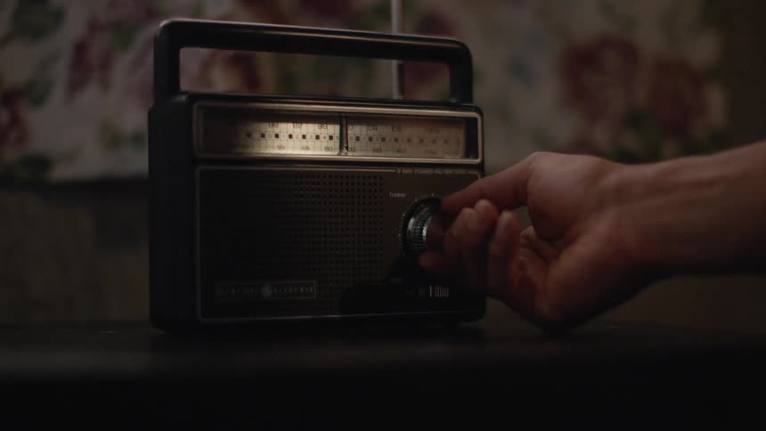 A white man tunes a portable radio