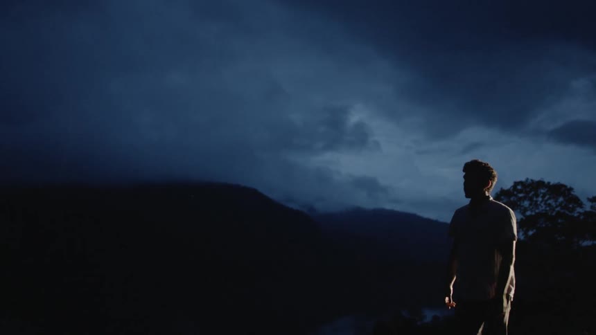 A man walks down a dark moonlit path at night