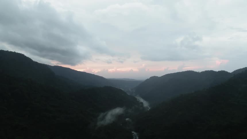 Fog hangs over the tree tops in the valley between forest covered hills