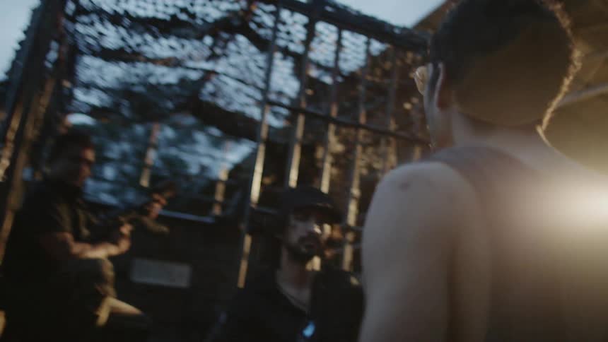 A man approaches people holding guns and a cigar