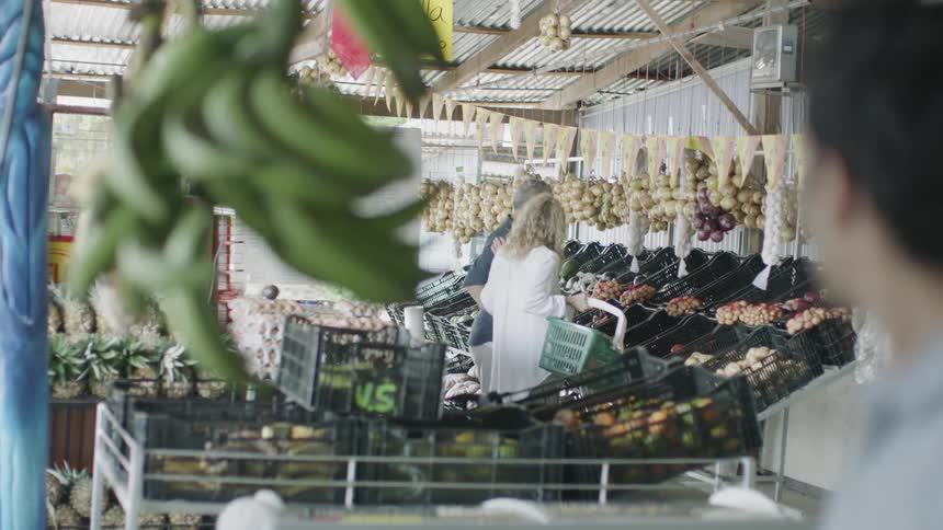 Man stands among produce in market looking
