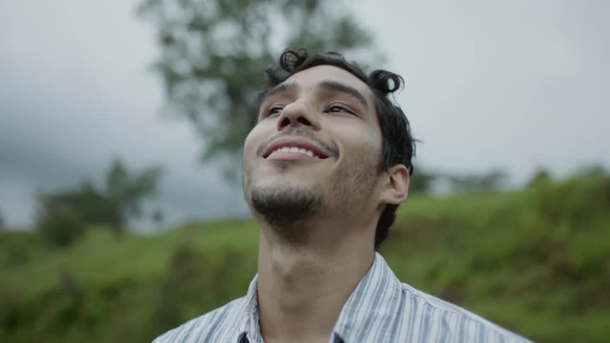 A man standing outdoors taking a deep breathe and looking up at the sky