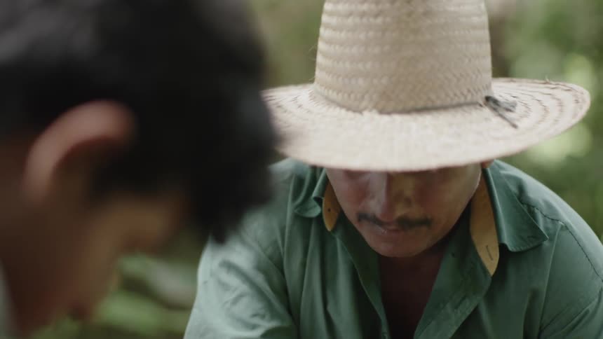 A man kneeling beside and speaking to a young man