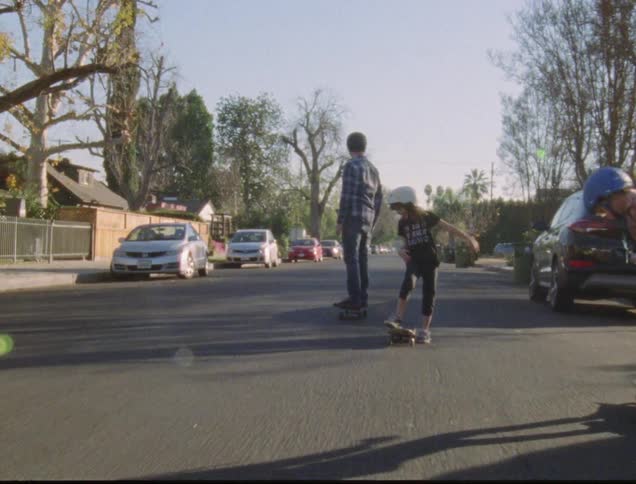 Man son and daughter skateboard on asphalt road during daylight