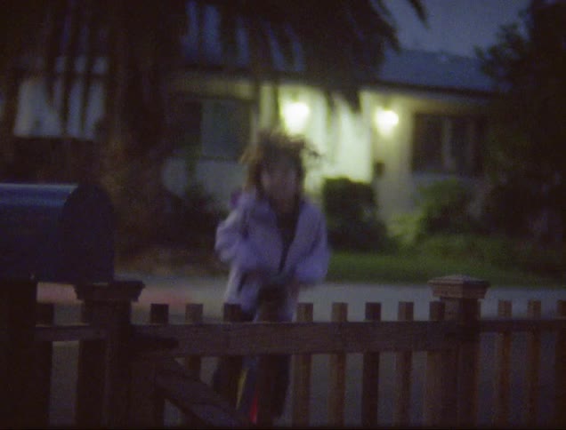 Girl jumps on pogo stick at dusk in front of fence