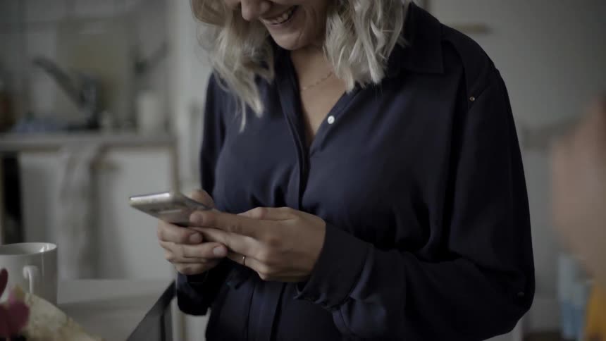 A woman using a smartphone in a kitchen