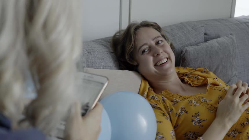 Two women laugh at something they are viewing on the phone