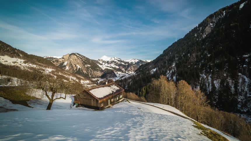 A log cabin sits on a snowy hillside