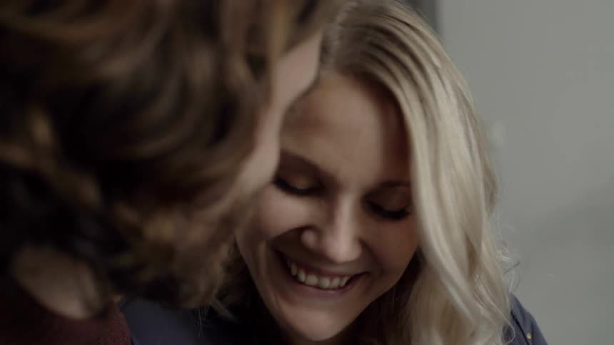 Brown hair woman talks to blonde woman who is smiling during daylight