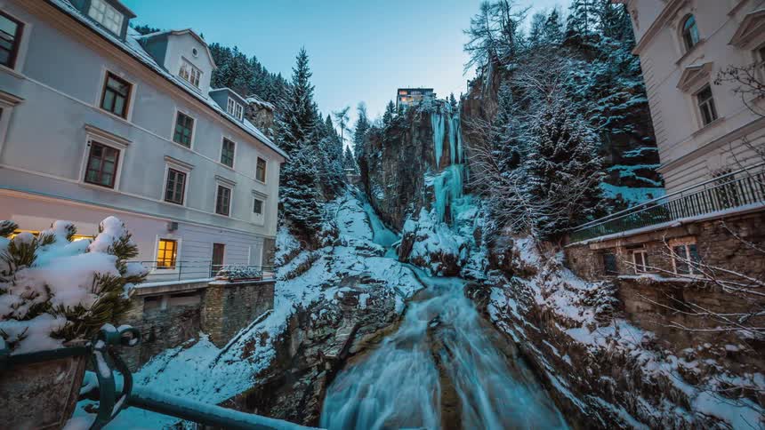 Frozen stream of water from the mountain goes between two town buildings