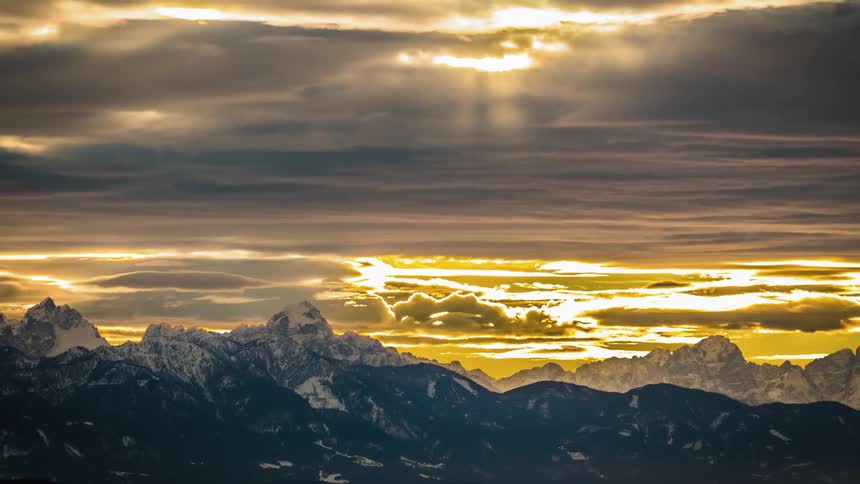 Cloudy skies passing over snow covered mountains