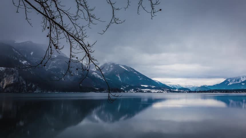 Fog rolling across a lake surrounded by snow covered mountains