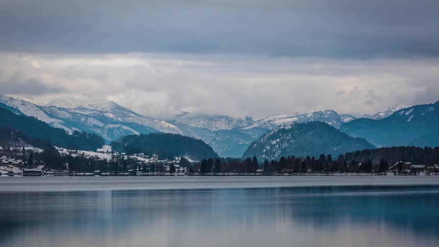 Storm clouds pass over a snowy mountain lake in the wilderness
