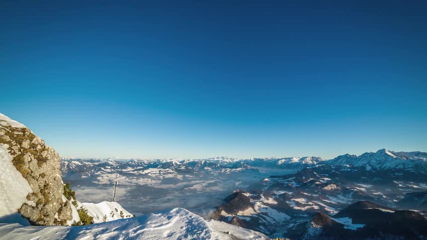 A cross sits on top of a mountain peak