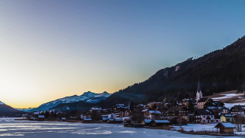 Smoke flow over snow covered town near mountain as night fall