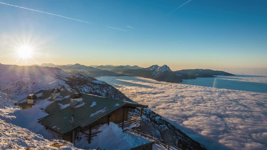 Mountain hut on a slope above the whirling clouds