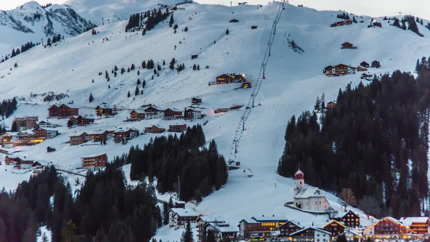 Ski resort with skiers day skiing and snow cats plowing at night