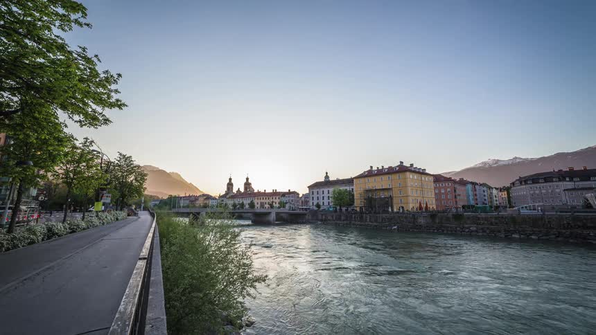 A wide river flows between a city and a long walkway for pedestrians