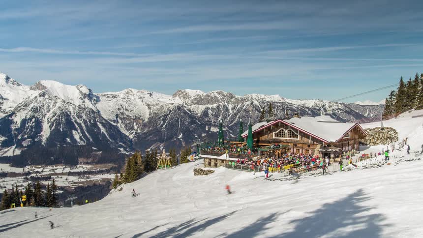 People ski at a mountain resort as clouds pass overhead